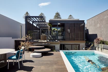 Azulejos blancos de la serie ‘Sugie’ (Inax) revisten el exterior de la piscina y el banco curvo acompañado por la mesa ‘Mesh’ y las sillas ‘Roll’, dos creaciones más con el sello de Urquiola para Kettal.