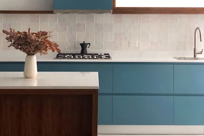 Azulejos nacarados de bordes irregulares (SBG). Mesada de Silestone "Calacatta Gold". Muebles de MFD laqueado en azul (Ideï Arquitectura). Bese de la isla y marco de la ventana de incienso.