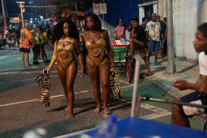 Bailarinas de la escuela de samba Paraiso do Tuiuti llevan sus tacones en la mano a un ensayo antes de las fiestas de Carnaval en Río de Janeiro, Brasil, el lunes 15 de enero de 2024. (AP Foto/Silvia Izquierdo)