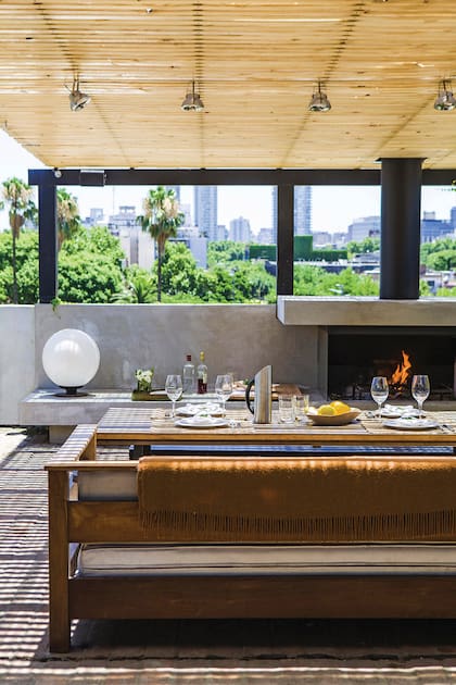 Bajo la pérgola con listones de madera que surge del volumen de la oficina, un hogar que es también parrilla. Foto: Santiago Ciuffo