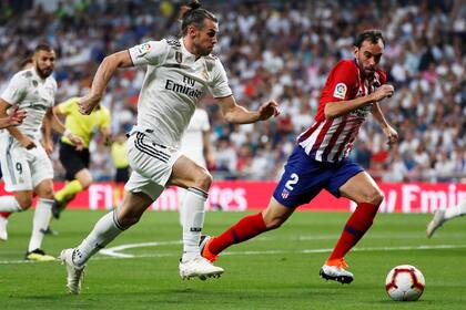 Bale y Godín disputan la pelota en el clásico madrileño.