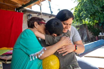 Baltazar abraza a Julia Ríos Serbian (izq.), fundadora y directora del Hogar Milagros, y a Karla Toro Toro, una de sus responsables