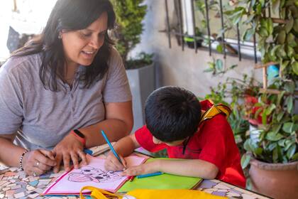 Baltazar colorea un cuaderno acompañado por Karla, en el jardín del hogar donde vive desde que tiene tres años.
