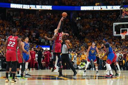 Bam Adebayo (13), del Heat de Miami, y Nikola Jokic, de los Nuggets de Denver, detrás, brincan en el arranque del Juego 1 de las Finales de la NBA, el jueves 1 de junio de 2023, en Denver. (AP Foto/Jack Dempsey)