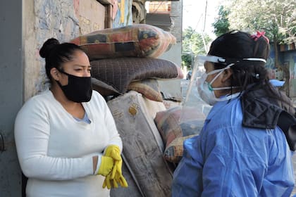 La promotora de salud Bania Quispe junto a una vecina del Barrio 31 en una de sus recorridas diarias