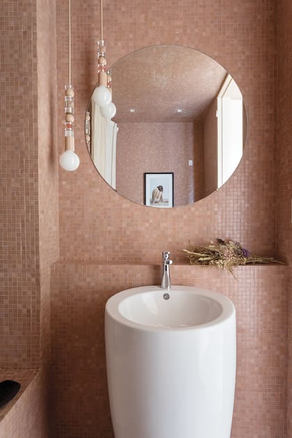 Baño, en mosaicos venecianos de un divino tono rosado, nuevamente con un aplique colgante ‘Ábaco’ (Estudio Molé). Lavatorio pedestal ‘Milos’ (Ferrum) con grifería ‘Aromo’ (FV). Estudio Trama Experiencia Casa living