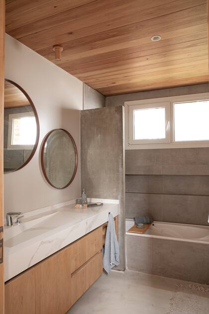 Baño en suite con mesada de Neolith 'Quarzo' con bacha integrada, vanitory de lenga (todo realizado por Rossini) y paredes de microcemento.