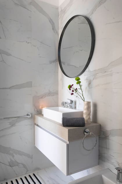Baño revestido en porcelanato rectificado ‘Calacata’ (San Lorenzo Design), bacha (Ferrum) con grifería (FV) y toalla (Lote Propio).