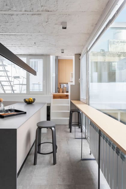 Barra con tapa de MDF enchapado en haya blanca y patas de planchuela metálica (Arq. Flor Fontana). Banquetas (tortuga.ar). Los escalones llevan al living-comedor