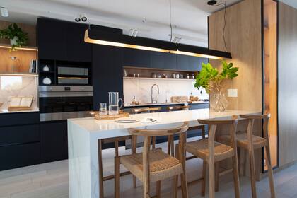 Barra de Dekton ‘Natura’ (Canteras del Mundo), lámpara colgante (La Feliz), banquetas (Marini) y vaso con arreglo verde (Ciudad Naturaleza).