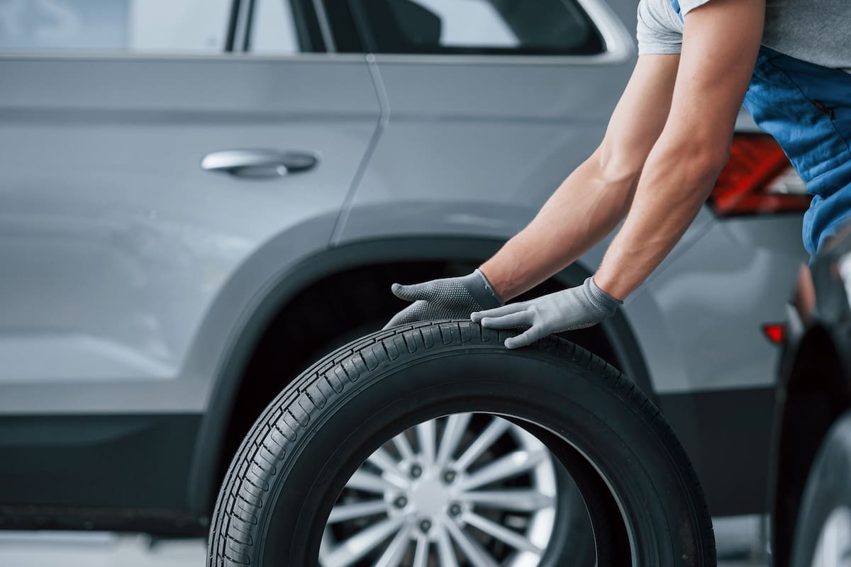Be right back. Mechanic holding a tire at the repair garage. Replacement of winter and summer tires.