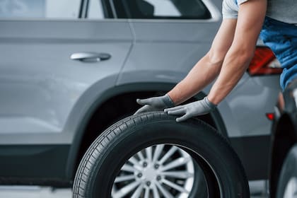 Be right back. Mechanic holding a tire at the repair garage. Replacement of winter and summer tires.