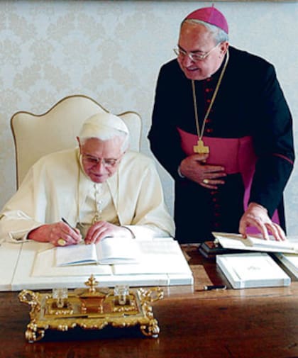 Benedicto XVI firma la encíclica; lo acompaña el arzobispo argentino Sandri