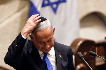 Benjamin Netanyahu se ajusta la kipá después de hablar en una sesión especial de la Knesset, el Parlamento de Israel, antes de asumir como primer ministro, en Jerusalén, el jueves 29 de diciembre de 2022. (Amir Cohen/Pool Photo vía AP)
