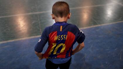 Benjamin Palandella se viste de su camiseta de Barcelona adornada con el número 10 de Messi después de un partido de entrenamiento en la academia de fútbol juvenil Club Social Parque en un barrio de clase trabajadora de Buenos Aires, Argentina. Después del juego de entrenamiento, Benjamin siguió pat