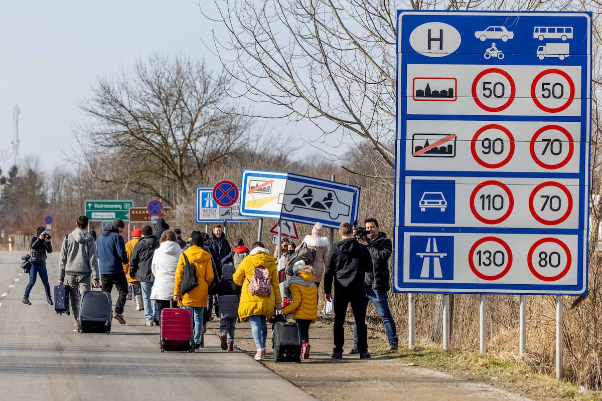 BEREGSURANY, HUNGARY - FEBRUARY 25: People walk with their belongings at the Astely-Beregsurany border crossing as they flee Ukraine on February 25, 2022 in Beregsurany, Hungary. Long queues have already formed at the Hungarian-Ukrainian border crossings after Russia began a large-scale attack on Ukraine in the early hours of February 24, with explosions reported in multiple cities and far outside the restive eastern regions held by Russian-backed rebels. (Photo by Janos Kummer/Getty Images)
