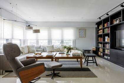 Biblioteca (Crudo Home). El sofá se hizo a medida y los banquitos y la mesa se reciclaron: los primeros, laqueados en un tono más claro que la biblioteca; la segunda, con un enchapado en roble (todo de Crudo Home). Lámparas suspendidas con contrapeso (Gris Dimensión)