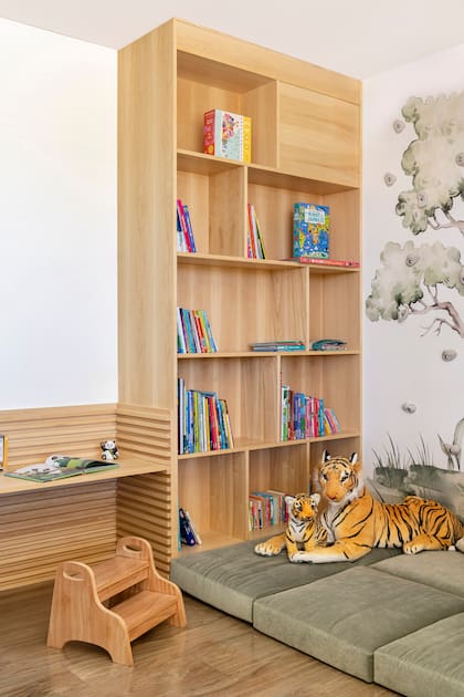 Biblioteca de guatambú y escritorio con ranuras para modificar la altura de la mesa (Malé). Almohadones a medida con género de Tienda Mayor.