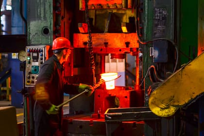 Blacksmith processes the red hot iron under a huge press. Metal forging, stamping under hammer forge at workshop of forge foctory. Blacksmithing, metallurgical, steelmaking, hot rolling mill