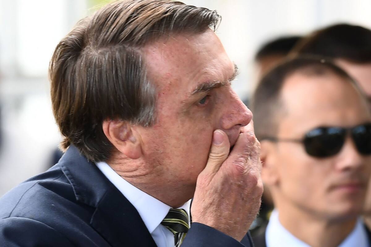 Bolsonaro se tapa la boca, ayer, al salir del Palacio de la Alvorada, en Brasilia