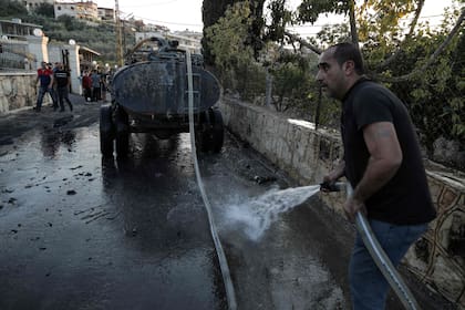 Bomberos improvisados limpian la escena del ataque israelí contra el vehículo donde viajaba el comandante libanés Ismail Yusaf Baz