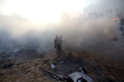 Bomberos palestinos tratan de extinguir un incendio en un edificio destrozado tras un ataque aéreo israelí en la ciudad de Gaza, el miércoles 25 de octubre de 2023