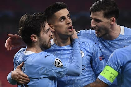 Bernardo, João Cancelo y Ruben Días, tres portugueses de Manchester City, festejan el gol del primero durante el partido contra Borussia Mönchengladbach, por la ida de los octavos de final de la Champions League.