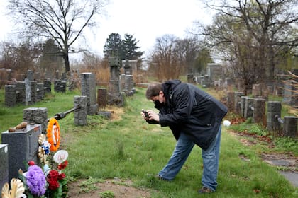 Brian Walter toma una fotografía de la lápida de su difunto padre en el cementerio All Faiths en el distrito de Queens de Nueva York