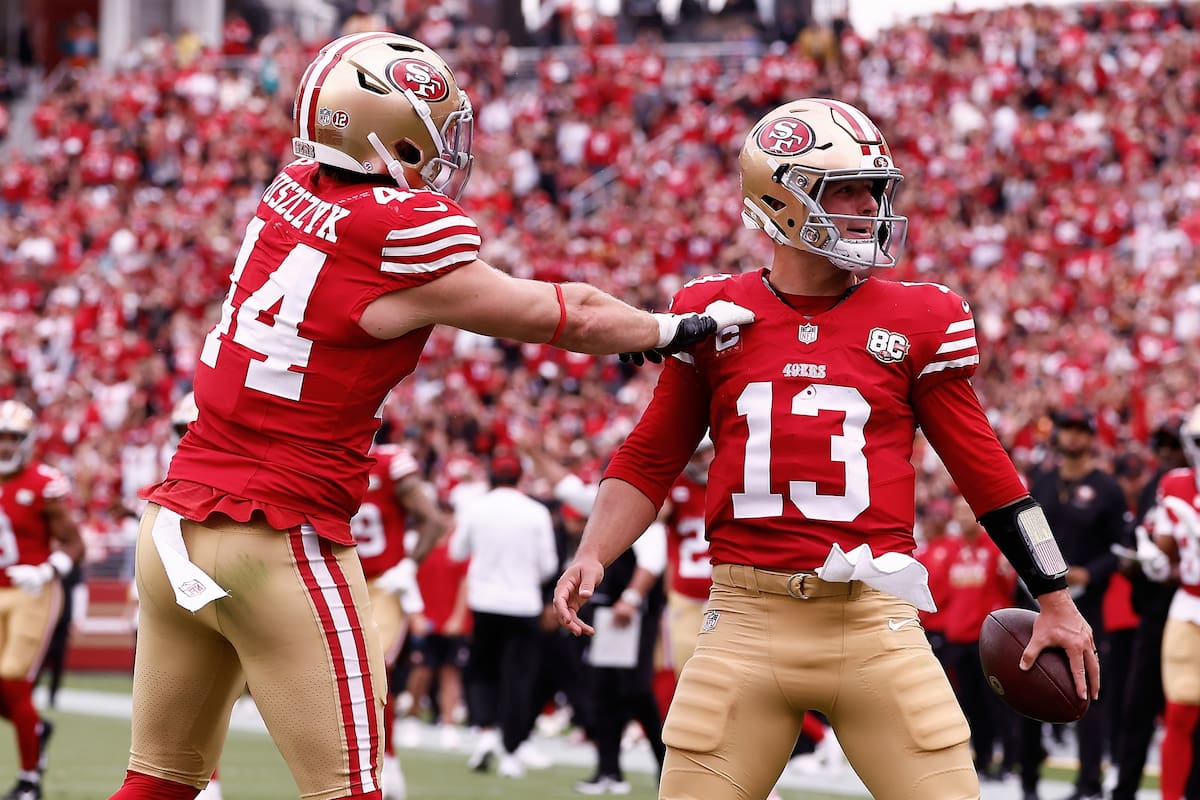 Brock Purdy (13), quarterback de los 49ers de San Francisco, es felicitado por el fullback Kyle Jusz