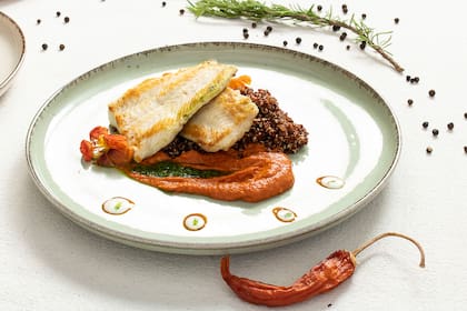 Brótola grillada sobre risotto de quinoa roja, salsa de vegetales asados y pimentón dulce.