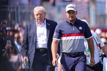 Bryson DeChambeau camina junto al presidente Donald Trump en la primera jornada de la competencia por la Copa Ryder, en Nueva York; Estados Unidos necesita reponerse ante Europa.