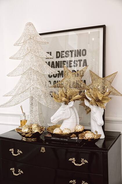 Cabezas de cebra y de cabra en resina blanca de Muy Arzuaga intervenidas con flores doradas de SheShu. Árbol móvil blanco con brillos de SheShu. Hojas de metal dorado como bandejas con esferas navideñas de diseño de Agustina Cerato