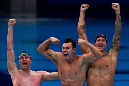 Caeleb Dressel (derecha)., Blake Pieroni (centro) y Bowen Becker (izquierda) celebran su victoria para llevarse el oro en la final del evento masculino de natación de relevos 4x100m estilo libre durante los Juegos Olímpicos de Tokio 2020 en el Centro Acuático de Tokio.