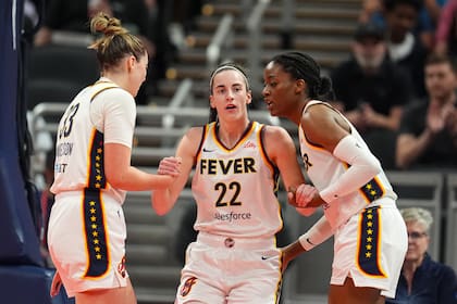 Caitlin Clark (22), del Fever de Indiana, es asistida para ponerse de pie por sus compañeras de equipo, Katie Lou Samuelson (33) y Temi Fagbenle (14) en la primera mitad del juego de baloncesto de la WNBA en contra del Sun de Connecticut, el lunes 20 de mayo de 2024, en Indianápolis. (AP Foto/Michael Conroy)