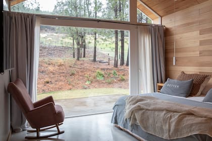Cama con acolchado de tussor, almohadones grises con inscripcion (todo de Ganga Home), almohadones 'Rococó' tejidos y manta rústica calada (todo de Alma Nómade Deco).