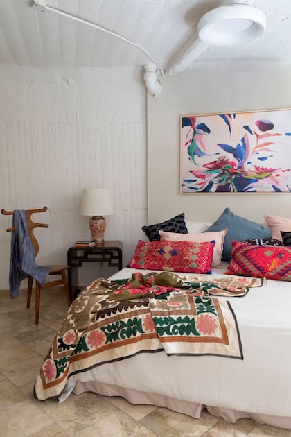 Cama con blanquería de Melissa Domit. Almohadones de terciopelo y seda (todo de Desde Asia). Lámpara ‘Fuegos’ (Desde Asia). Obra ‘Otra Galaxia’, de Daniela Achoyan (Galería Pared).