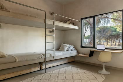 Camas con barandas y estructura de chapa y madera diseñadas por Ábaton. Silla ‘Tulip’ vintage (Pez).