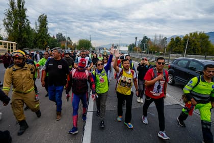 Camila Gómez, en el centro, madre de un niño de 5 años con distrofia muscular de Duchenne, saluda mientras camina 1.000 kilómetros desde Ancud hasta Santiago, Chile, el martes 28 de mayo de 2024, para recaudar los fondos que necesita para el tratamiento médico de su hijo. (AP Foto/Esteban Félix)
