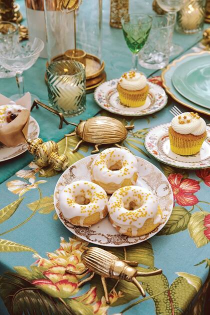 Camino central de pana de De Levie, sobre una tela estampada con flores. Donas de vainilla real navideñas y cupcakes con buttercream de limón, de @houseofcupcakesargentina