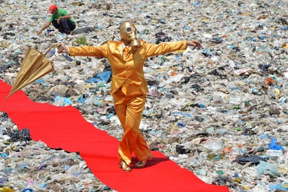 Una performer de alfombra roja interviene un basural en Brasil, en la obra de Berna Reale