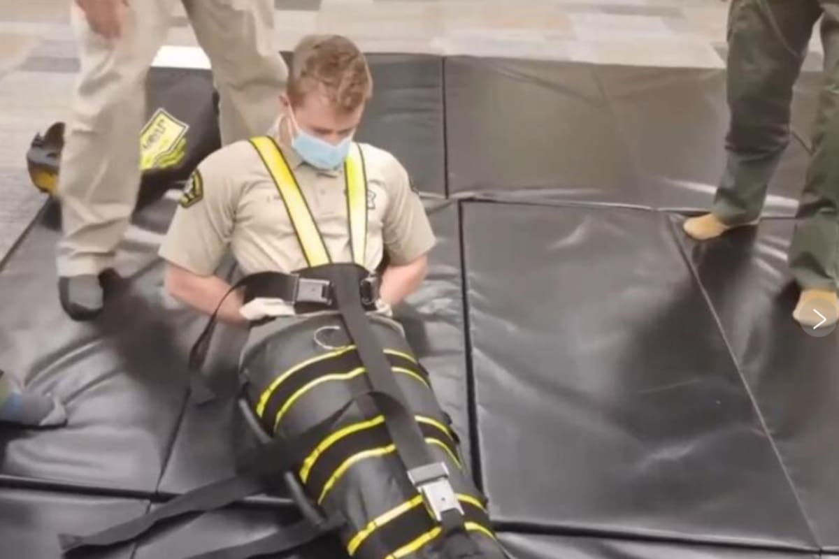 Captura de video de los agentes del ICE utilizando el dispositivo de inmovilización corporal completa llamado WRAP. Fuente: AP/Allen G. Breed