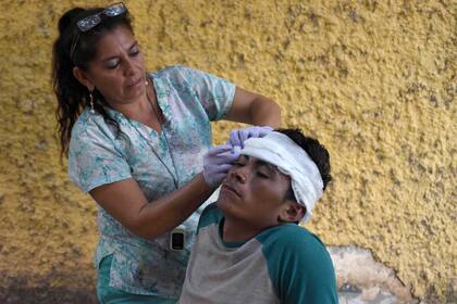 Una mujer ayuda a un migrante herido y que participa de la caravana que se dirige a EE.UU.