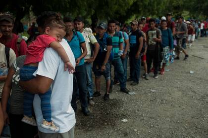 Los migrantes hondureños forman una fila para recibir alimentos donados