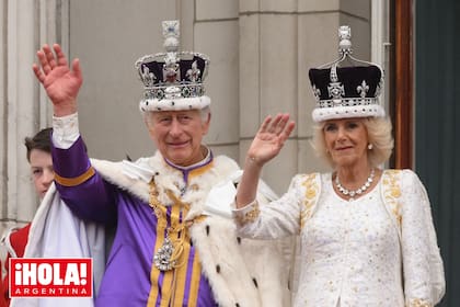 Carlos III y Camilla saludando desde el balcón del Palacio de Buckingham con sus respectivas coronas.