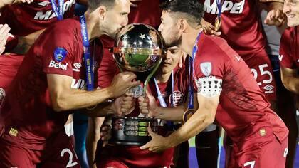 Carlos Izquierdoz y Lautaro Acosta besan la Copa Sudamericana ganada por Lanús el mes pasado en Asunción, Paraguay, al derrotar por penales a Mineiro.