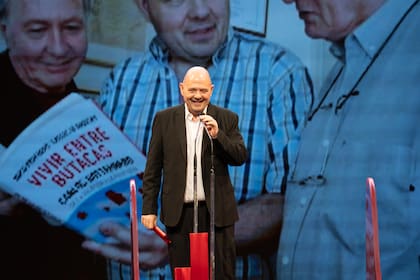 Carlos Rottemberg recibiendo el Premio Pinti con imagen de fondo del libro de Paredero y Ulanovsky sobre su propio recorrido