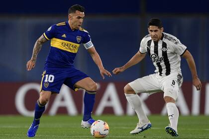 Carlos Tevez de Boca Juniors disputa la pelota con el defensor Diego Viera de Libertad