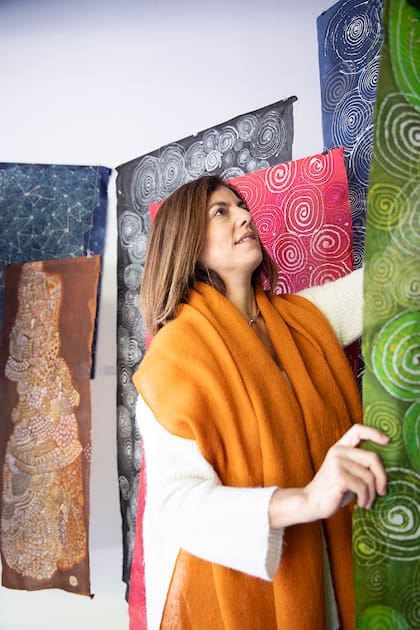 Carola Cohen admirando varias obras de la artista Dina Straus realizadas con la técnica batik.