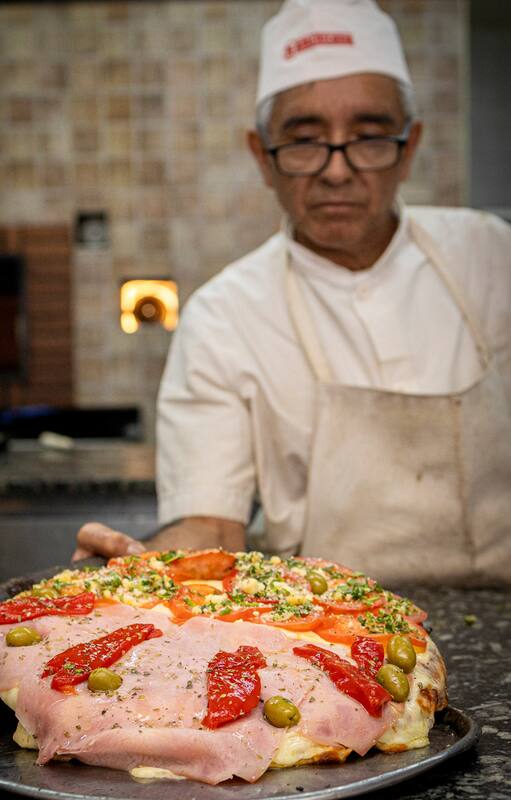Carola Santoro, de Ti Amo, con una pizza "napoletana", y uno de los pizzeros de la Americana, con una clásica porteña de media masa