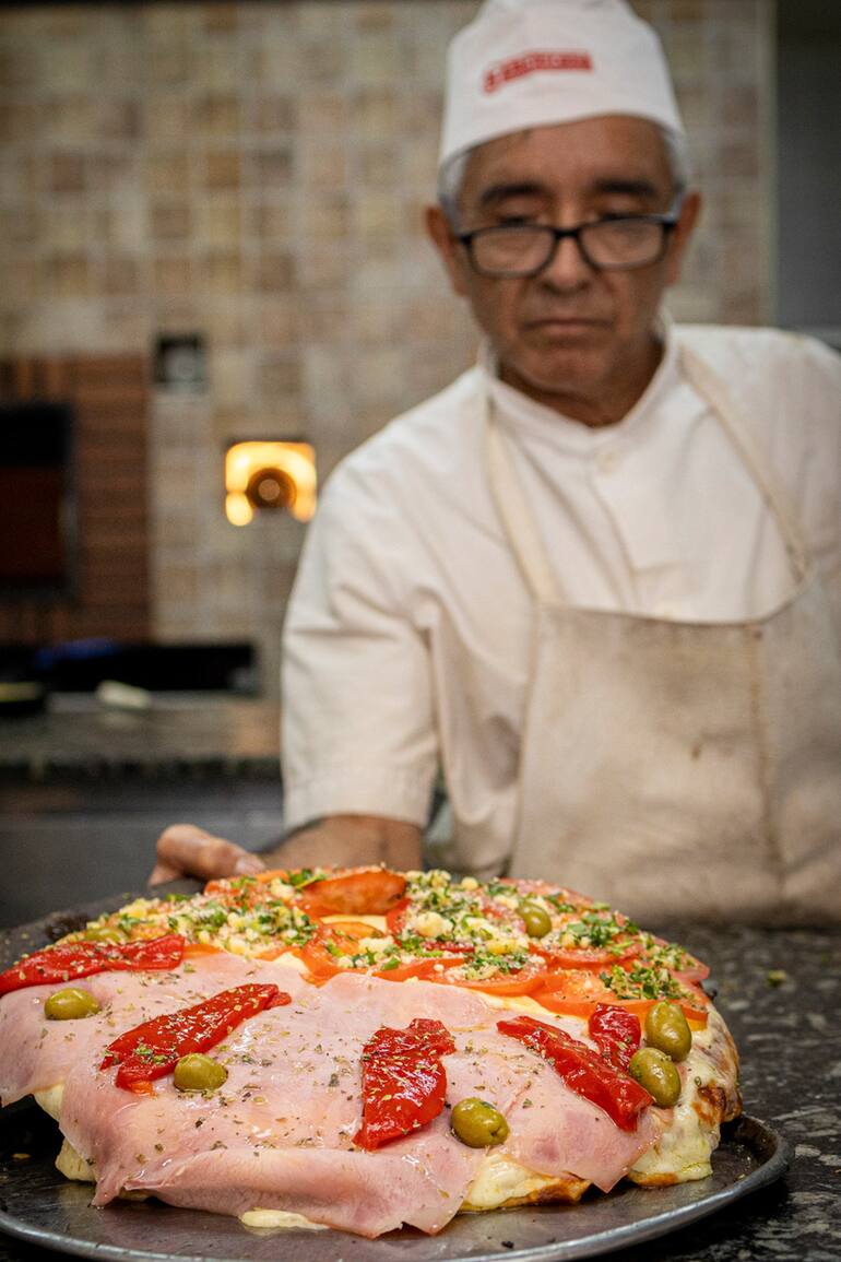 Carola Santoro, de Ti Amo, con una pizza "napoletana", y uno de los pizzeros de la Americana, con una clásica porteña de media masa